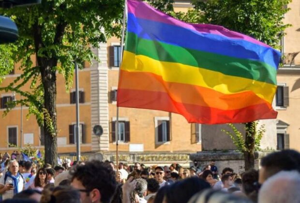 People holding a big Rainbow flag