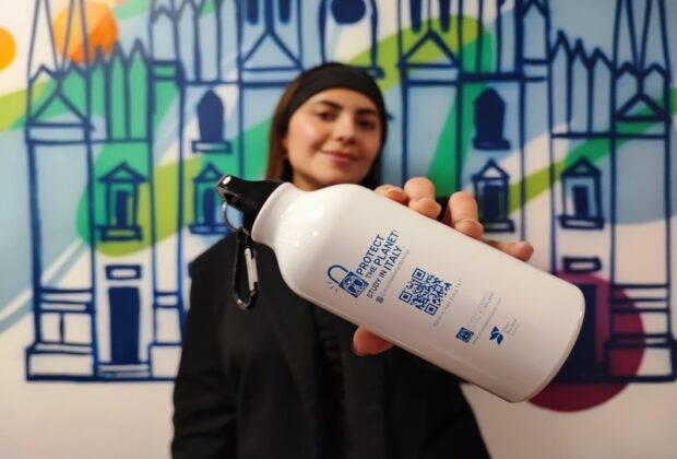 girl in the background of the colored wall holding a reusable water bottle
