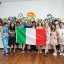 students holding an italian flag in front of a wall painted with murals