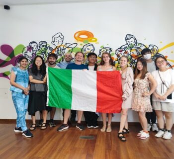 students holding an italian flag in front of a wall painted with murals