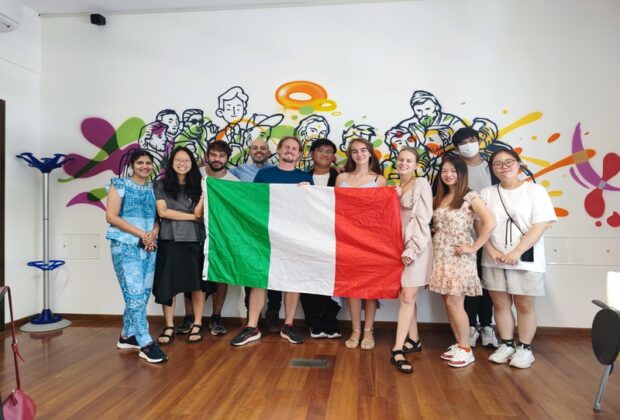 students holding an italian flag in front of a wall painted with murals